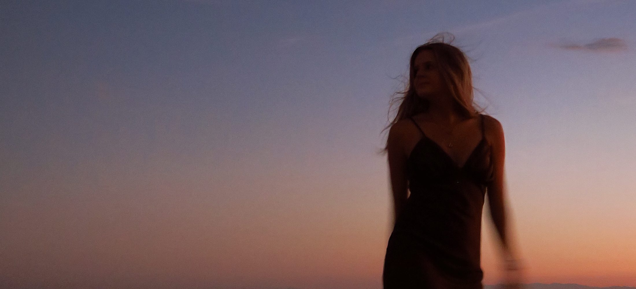 Une femme seule sur une dune, à l'heure bleue, la lune au-dessus d'elle